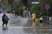 People make their way on a flooded street in Campi di Bisenzio, in the central Italian Tuscany region, Friday, Nov. 3, 2023. Record-breaking rain provoked floods in a vast swath of Tuscany as storm Ciaran pushed into Italy overnight Friday, trapping people in their homes, inundating hospitals and overturning cars. At least three people were killed, and four were missing. (AP Photo/Gregorio Borgia)