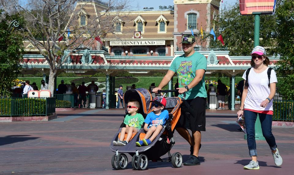 Children are pushed in their stroller as a family visits Disneyland.