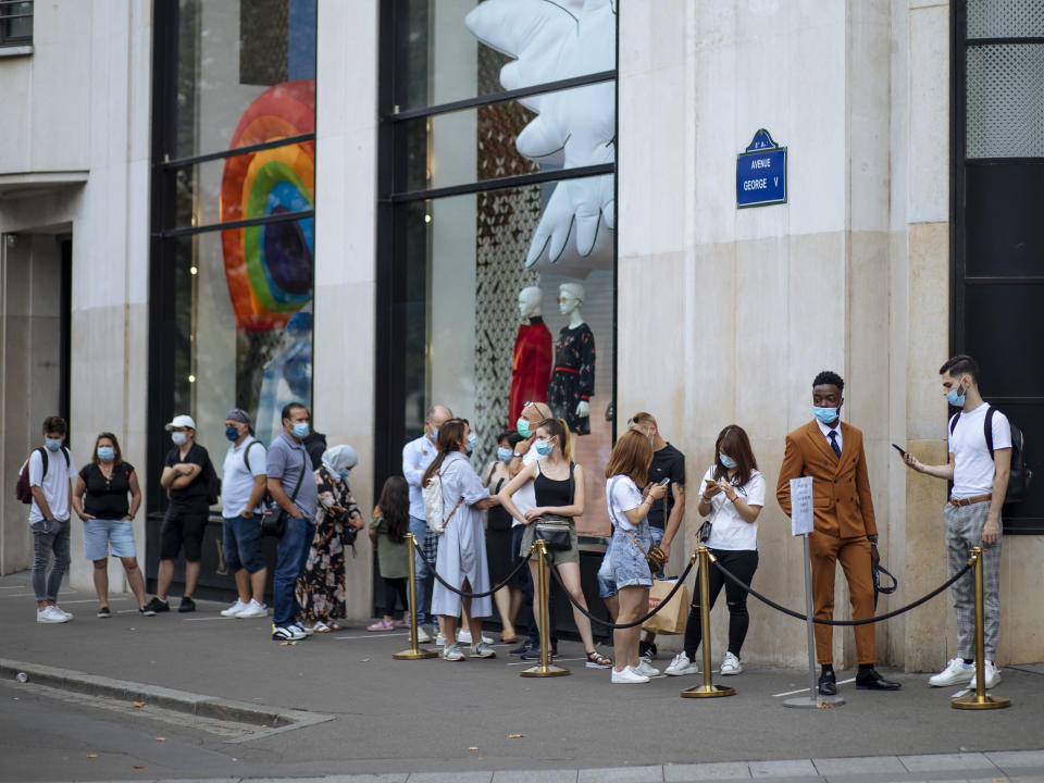 People with face masks queue as they wait to get in the Louis Vuitton shop on the Champs Elysee avenue in Paris, Saturday, Aug. 15, 2020. Paris extended the areas of the city where pedestrians will be obliged to wear masks starting Saturday morning after health officials said that the coronavirus is "active". The Champs-Elysees Avenue and the neighbourhood around the Louvre Museum are among zones where masks will be obligatory. (AP Photo/Kamil Zihnioglu)