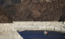 FILE - In this Oct. 14, 2015, file photo, a riverboat glides through Lake Mead on the Colorado River at Hoover Dam near Boulder City, Nev. For the seven states that rely on the Colorado River that carries snowmelt from the Rocky Mountains to the Gulf of California, that means a future with increasingly less water for farms and cities although climate scientists say it's hard to predict how much less. The U.S. Bureau of Reclamation on Thursday, Aug. 15, 2019, will release its projections for next year's supply from Lake Mead, which feeds Nevada, Arizona and California. (AP Photo/Jae C. Hong, File)