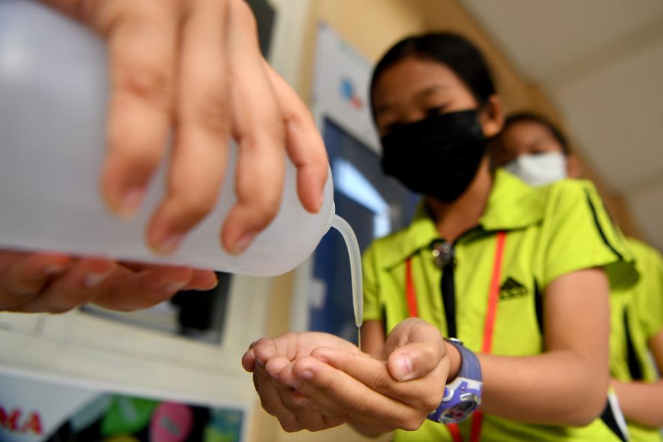 Students disinfect their hands with an alcohol solution before entering class at a school in Phnom Penh, Cambodia.