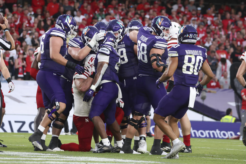 Northwestern running back Cam Porter, center, celebrates with teammates after scoring a on a 3-yard touchdown run during the second half of an NCAA college football game against Nebraska, Saturday, Aug. 27, 2022, at Aviva Stadium in Dublin, Ireland. (AP Photo/Peter Morrison)