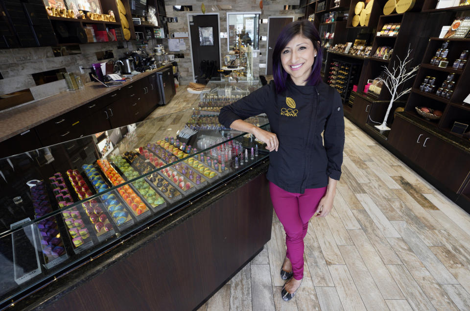 In this Monday, Sept. 16, 2019, photo Annie Rupani, owner of Cacao & Cardamom, poses inside one her shops in Houston. She's seen the amount that people spend on each visit drop in the past year. Like many retailers, she's going to put more effort and investment into her online business. (AP Photo/David J. Phillip)