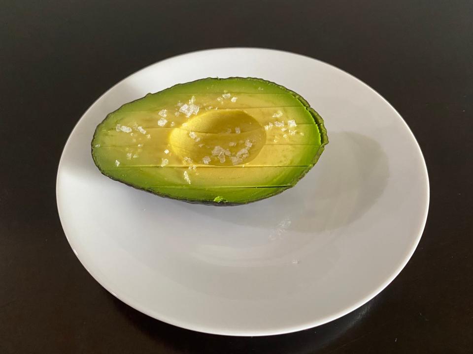 A half avocado sliced but still in peel with flaky salt on top