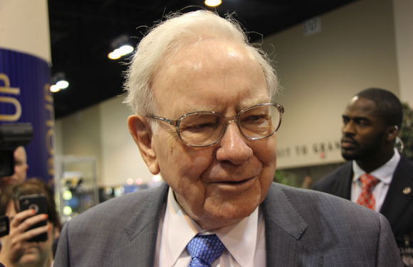 Warren Buffett speaks with people in a crowd at a conference.