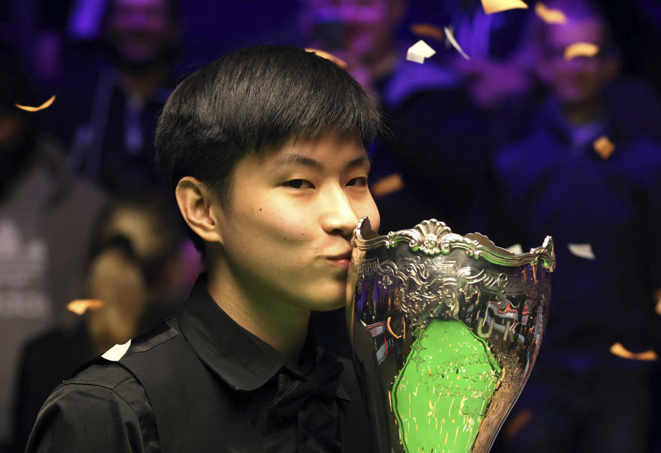 China's Zhao Xintong kisses the trophy after winning the final of the Cazoo UK snooker Championship at the York Barbican, England, Sunday, Dec. 5, 2021. (Richard Sellers/PA via AP)