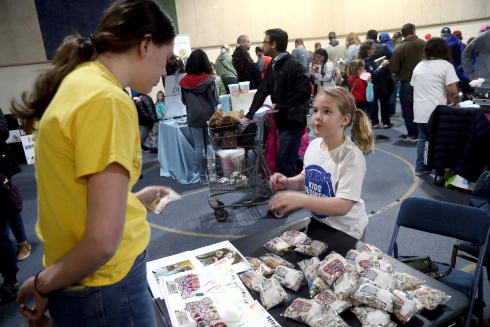 Ruby Gill, 8, of Dublin, sells Sara Oates of Hilliard puppy chow snacks from her Ruby's Puppy Yummy Chow!! booth at the Kids' Business Fair on April 9 at the Hilliard United Methodist Church's Warehouse 839.