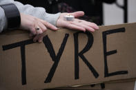 A demonstrators holds a sign and candle as they protest outside a police precinct in response to the death of Tyre Nichols, who died after being beaten by Memphis police officers, in Memphis, Tenn., Sunday, Jan. 29, 2023. (AP Photo/Gerald Herbert)