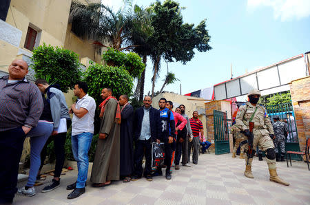 An Egyptian soldier stands guard as people wait in line to cast their votes during the second day of the referendum on draft constitutional amendments, at a polling station in Cairo, Egypt April 21, 2019. REUTERS/Amr Abdallah Dalsh