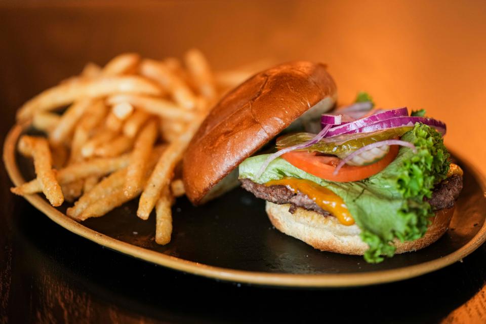 A saucy Barrel House burger topped with various ingredients and a side of fries.