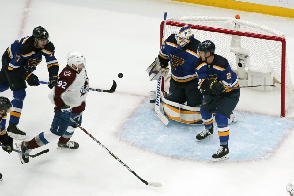 Colorado Avalanche's Gabriel Landeskog (92) keeps his eye on the puck as St. Louis Blues goaltender Ville Husso, Tyler Bozak, left, and Niko Mikkola, right, defend during the second period in Game 3 of an NHL hockey Stanley Cup second-round playoff series Saturday, May 21, 2022, in St. Louis. (AP Photo/Jeff Roberson)