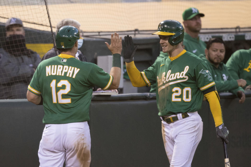 Oakland Athletics' Sean Murphy (12) celebrates with Mark Canha (20) after scoring a run against the Los Angeles Angels during the fifth inning of a baseball game in Oakland, Calif., Monday, June 14, 2021. (AP Photo/John Hefti)