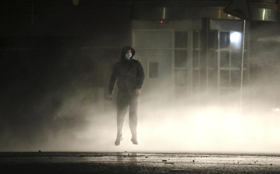 A Nationalist youth is lifted off the ground by a police water cannon near the Peace Wall in West Belfast, Northern Ireland, Thursday, April 8, 2021. Authorities in Northern Ireland sought to restore calm Thursday after Protestant and Catholic youths in Belfast hurled bricks, fireworks and gasoline bombs at police and each other. It was the worst mayhem in a week of street violence in the region, where Britain's exit from the European Union has unsettled an uneasy political balance. (AP Photo/Peter Morrison)