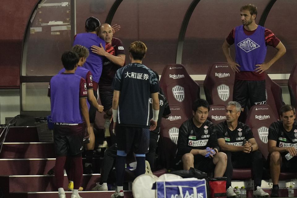 Vissel Kobe midfielder Andres Iniesta, center left back, gets a hug from his teammates after he was changed and got off the pitch during the second half of a friendly soccer match against Consadole Sapporo in Kobe, Japan, Saturday, July 1, 2023. The 39-year-old Spanish footballer plays his last match for the Japanese club Saturday. (AP Photo/Hiro Komae)