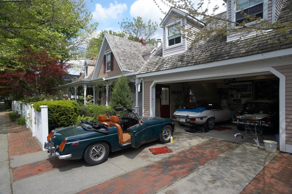 Tan home with garage containing three vintage cars. 