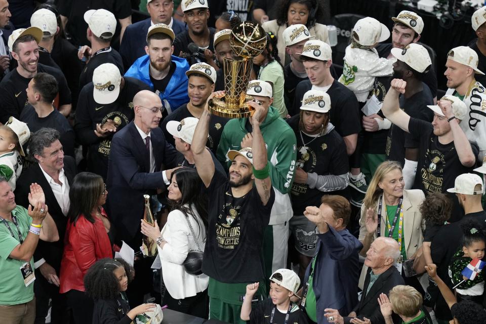 Boston Celtics' Jayson Tatum, center, raises the trophy after defeating the Dallas Mavericks in Game 5 of the NBA basketball finals, Monday, June 17, 2024, in Boston. (AP Photo/Michael Dwyer)