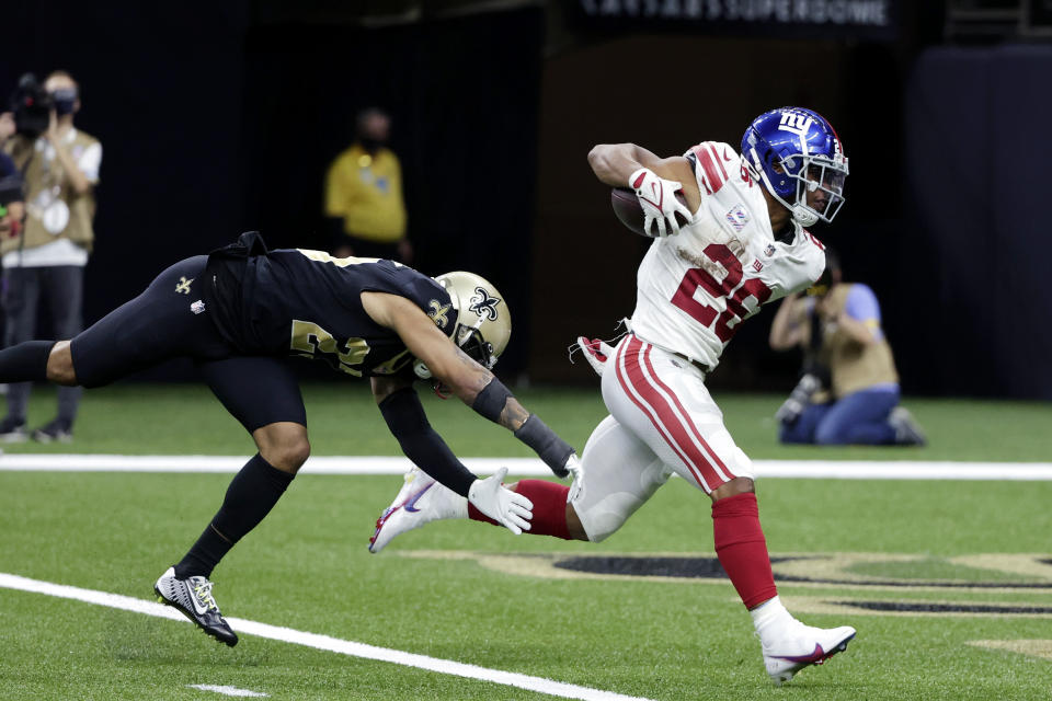 New York Giants running back Saquon Barkley (26) scores on a touchdown reception against New Orleans Saints cornerback Marshon Lattimore in the second half of an NFL football game in New Orleans, Sunday, Oct. 3, 2021. (AP Photo/Derick Hingle)