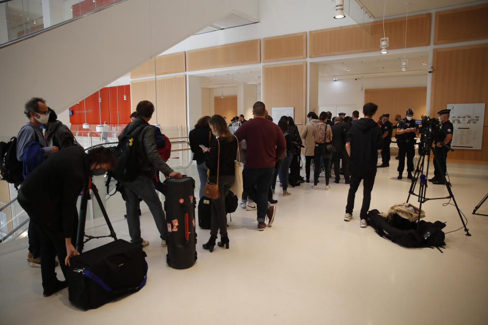 Journalists queue to enter the courthouse before the 2015 attacks trial, Wednesday, Sept. 2, 2020 in Paris. Most were petty criminals who supplied guns, ammunition, a car and bulletproof vests to the men responsible for the January 2015 attacks against a satirical newspaper, a kosher supermarket and a young policewoman. Seventeen people died along with the three attackers. (AP Photo/Francois Mori)