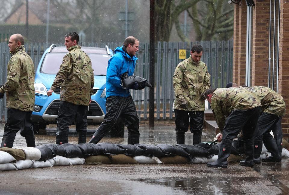 Britain's Prince William, The Duke of Cambridge, centre, unloads sandbags, with members of the armed forces, in Datchet, England, Friday Feb. 14, 2014. Prince William and Prince Harry helped flood-hit U.K. villagers protect their homes, unloading sandbags alongside soldiers in the River Thames village of Datchet. The princes, who have both served in the armed forces, joined a work crew Friday on what aides called a private visit. (AP Photo/Ki Price, PA) UNITED KINGDOM OUT - NO SALES - NO ARCHIVES