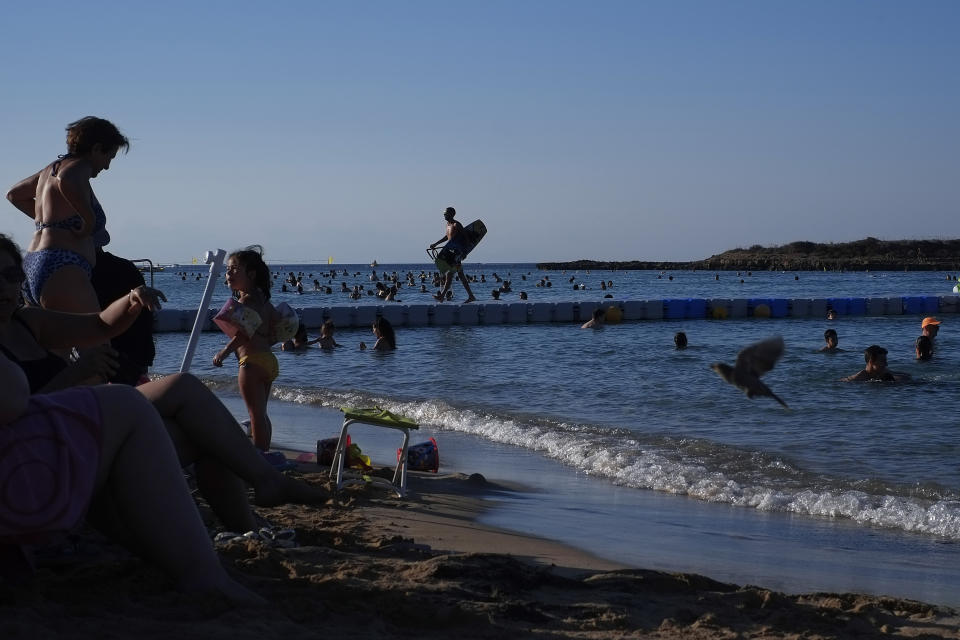 Swimmers cool off from the mid-summer heat in the clear east Mediterranean waters of Cyprus' Fig Tree Bay in the coastal resort of Protaras near Ayia Napa on Saturday, July 18 2020. Tourism-reliant Cyprus projects that this year, it will receive less than a quarter of the record 3.9 million holiday makers it got in 2019 because of the global coronavirus pandemic. (AP Photo/Petros Karadjias)