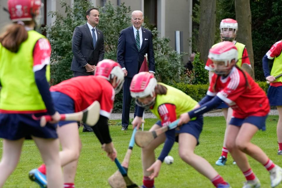 Biden and Ireland’s Taoiseach Leo Varadkar watch as girls play hurling during a youth Gaelic sports demonstration in Dublin on Thursday (AP)