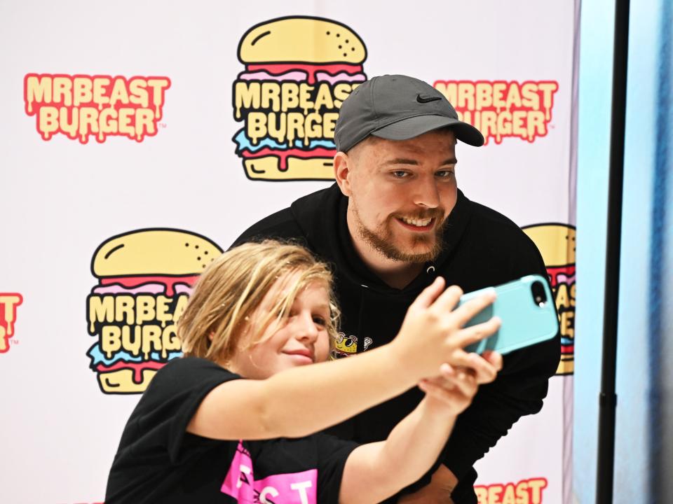 MrBeast takes a selfie with a fan at a MrBeast Burger event.