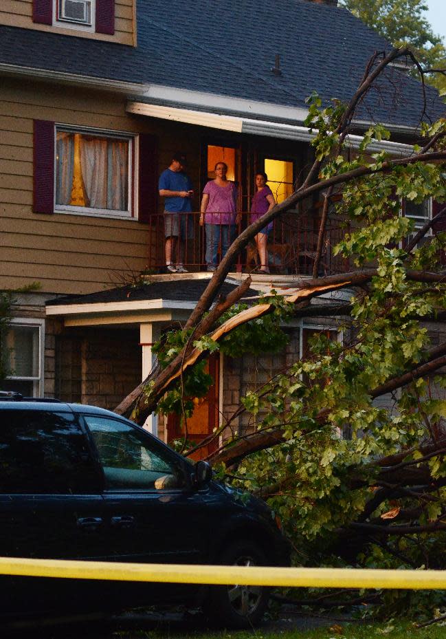 A family surveys the damage surrounding their property in Elmira N.Y., after a possible tornado struck the area, Thursday, July 26, 2012. The storm brought down trees and power lines, tore roofs off some buildings and caused motor vehicle accidents. Utilities report more than 20,000 customers without power in the area. (AP photos/Heather Ainsworth)