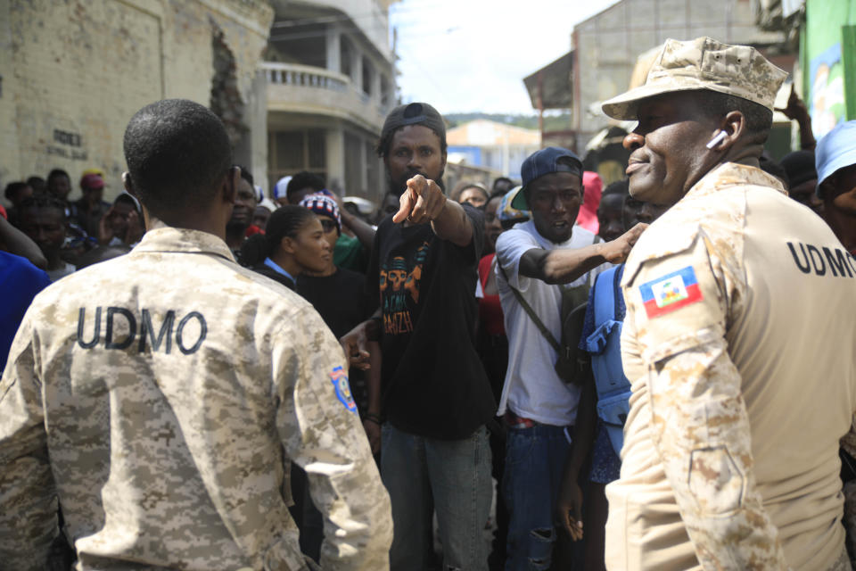 Police officers block a group of persons as they protest against the arrival of the USNS Comfort hospital ship in Jeremie, Haiti, Tuesday, Dec. 13, 2022. The USNS Comfort is on a humanitarian mission to provide dental and medical services. (AP Photo/Odelyn Joseph)