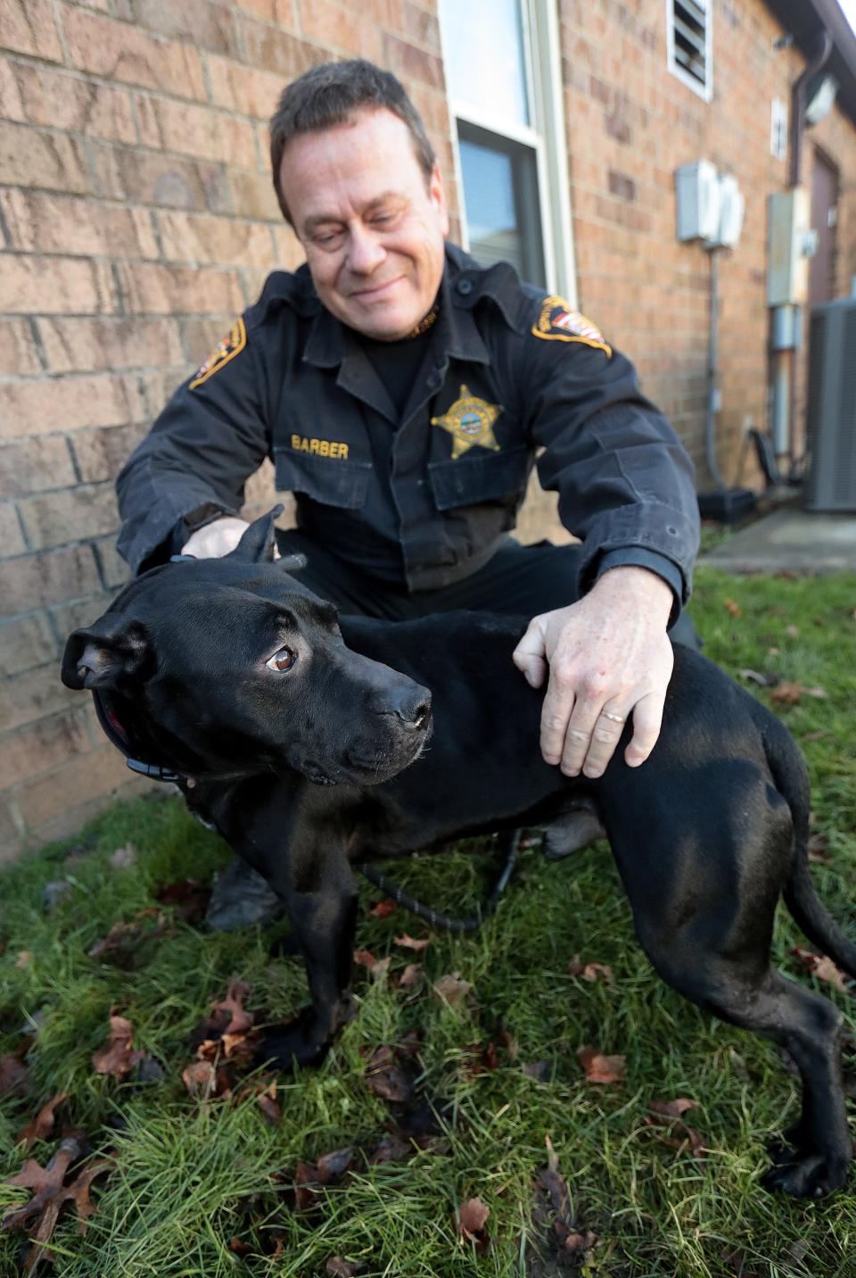 Stark County Deputy Sheriff Jon Barber, who oversees the dog warden division, pets Garth, a dog that is being treated for heart worms. The county is encouraging people to adopt a dog because it has too many at its facility.