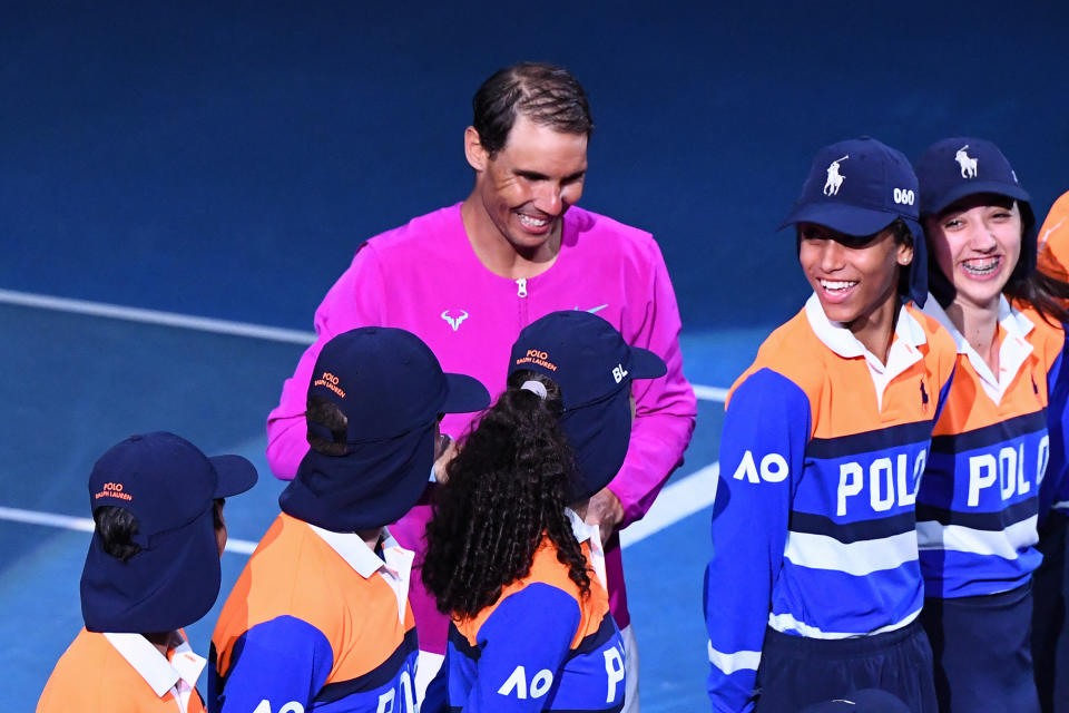 Rafael Nadal (pictured) smiles and holds the trophy as he poses with the ball kids after winning the Australian Open.