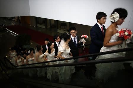 Couples take an escalator as they participate in a staged mass wedding, organised as part of a matchmaking event to inspire singles to get married, at a suburban area of Shanghai in this May 18, 2013 file photo. REUTERS/Carlos Barria