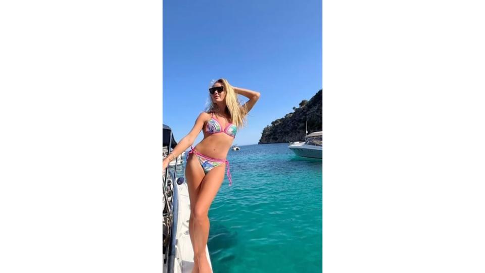 Amanda Holden hanging off the side of a boat in a bikini