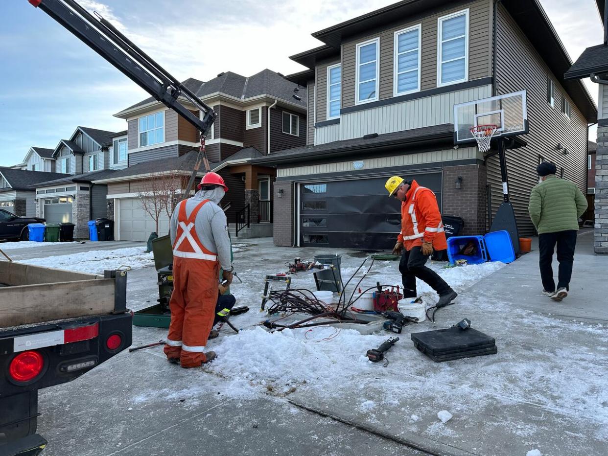 Crews work on fixing an Enmax electrical box that was taken out in an early Friday morning police chase in the northeast Calgary community of Saddle Ridge. (James Young/CBC - image credit)