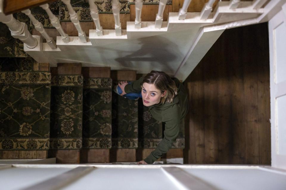 Bella Heathcote ascends a creepy set of stairs in an old house