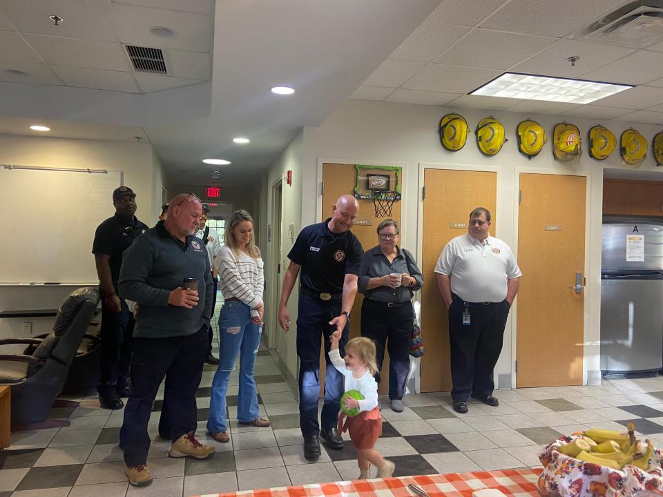 Alachua County firefighter Brandon Boothby holds the hand of his 1-year-old daughter Carter at an event Friday to celebrate his return to work after surviving a rare but severe blood disorder.