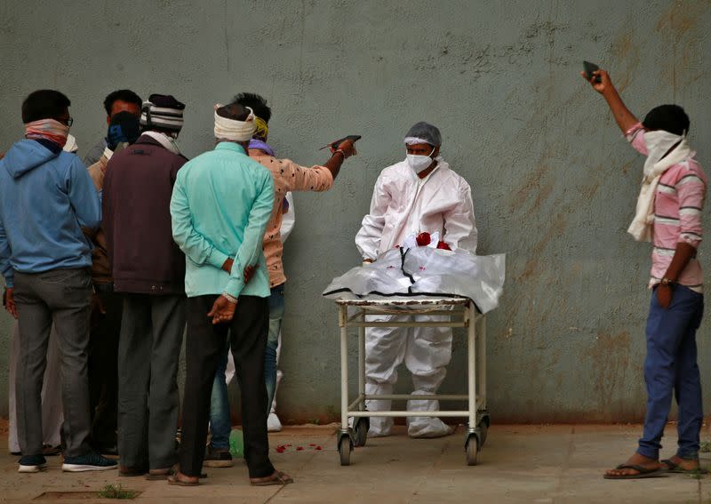 Men take photographs of the body of their relative after he died from the coronavirus disease (COVID-19) at a hospital in Ahmedabad