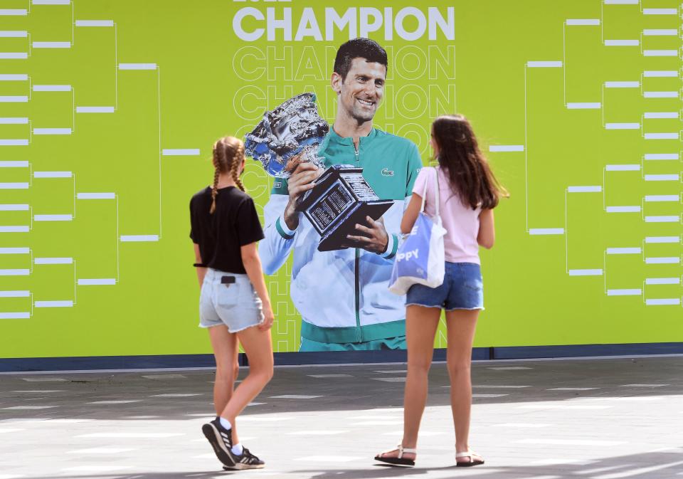 Dos personas contemplan una foto de Novak Djokovic en Melbourne. (Photo by WILLIAM WEST/AFP via Getty Images)