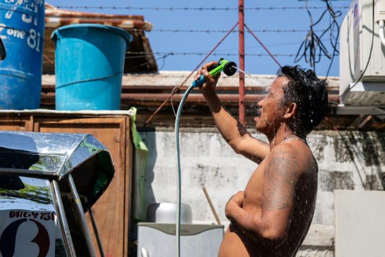A man showers with a hose during hot weather in Manila on April 28, 2024 (Earvin Perias)