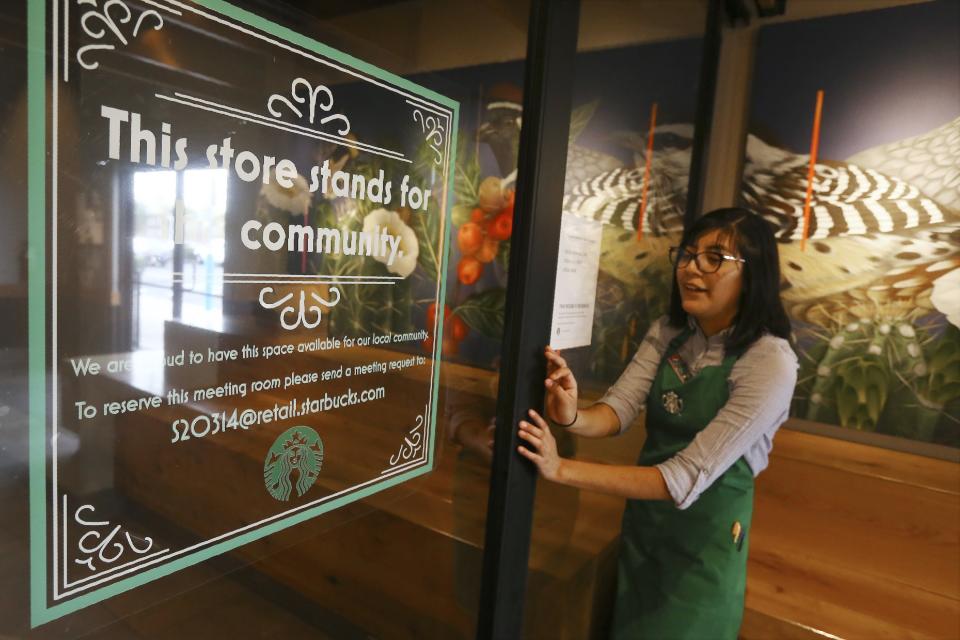 In this Wednesday, Jan. 15, 2020, photo, Belith Ariza, a barista trainer at Starbucks, opens the doors to the community meeting space at a local Starbucks Community Store, in Phoenix. The Seattle-based company plans to open or remodel 85 stores by 2025 in rural and urban communities across the U.S. That will bring to 100 the total number of community stores Starbucks has opened since it announced the program in 2015. (AP Photo/Ross D. Franklin)