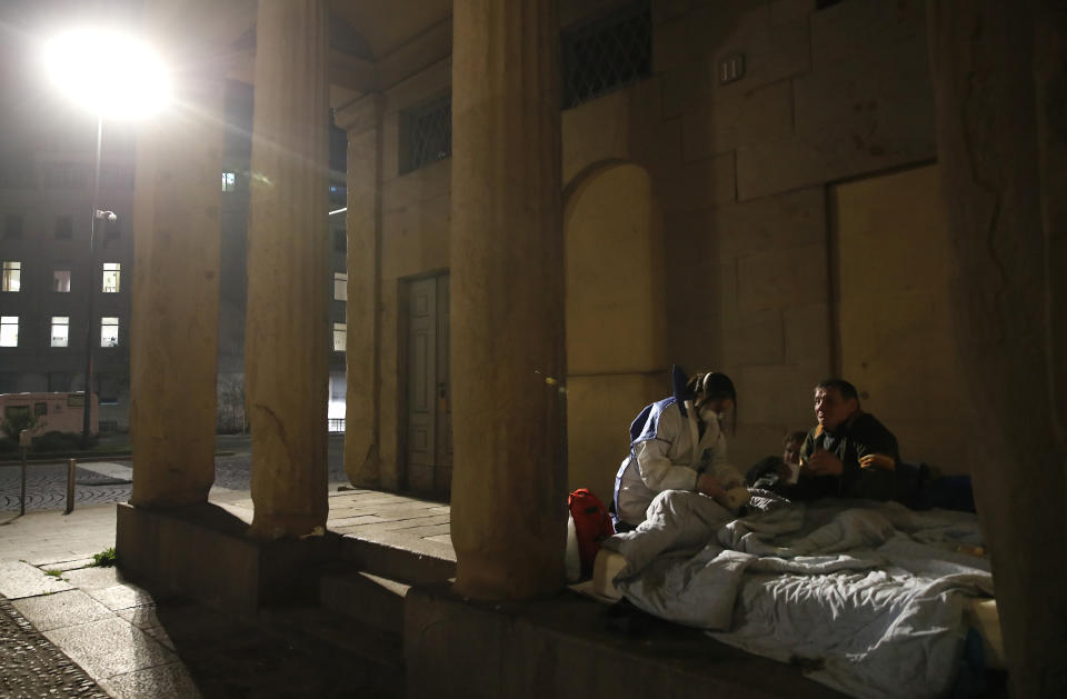 A volunteer nurse wearing a mask tends to homeless in Milan, March 24, 2020. (AP Photo/Antonio Calanni)