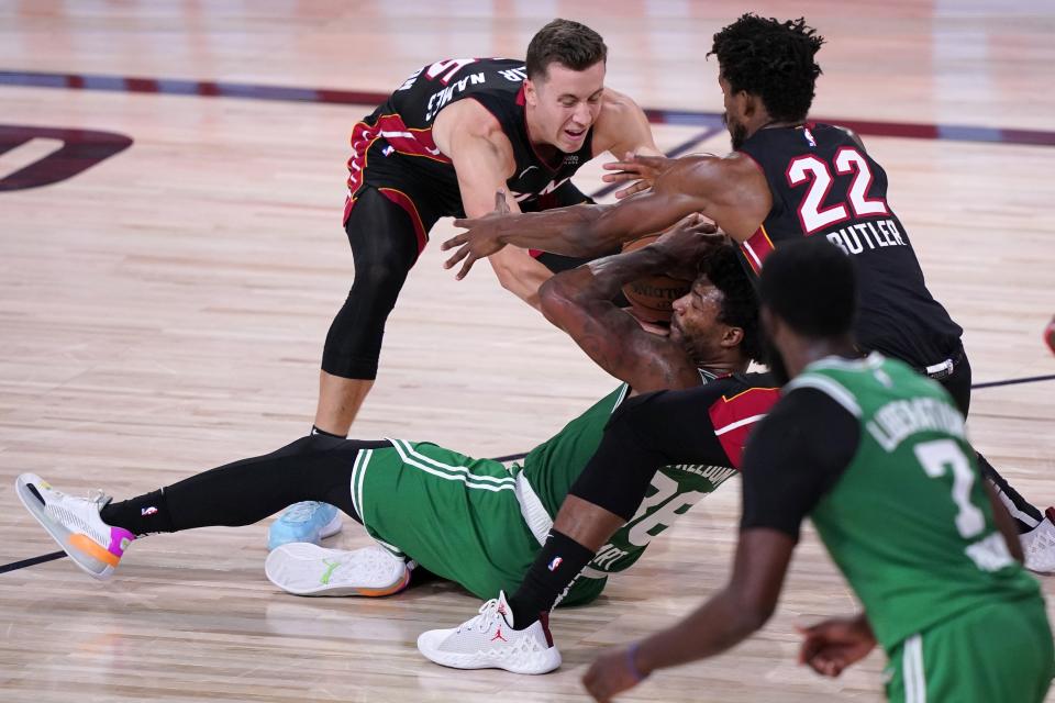 Boston Celtics' Jaylen Brown (7) looks on as Marcus Smart, center, struggles to maintain control of the ball against Miami Heat's Duncan Robinson, left, and Jimmy Butler (22) during the second half of an NBA conference final playoff basketball game, Saturday, Sept. 19, 2020, in Lake Buena Vista, Fla. (AP Photo/Mark J. Terrill)