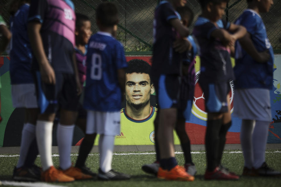 Jóvenes futbolistas entrenan en el Club Bayer de fútbol escolar, fundado por Luis Manuel Díaz, padre del jugador de la selección de Colombia y del equipo inglés Liverpool Luis Díaz, representado en una pintura en la pared al fondo, en Barrancas, Colombia, el miércoles 8 de noviembre de 2023. Luis Manuel Díaz fue secuestrado el 28 de octubre por la guerrilla Ejército de Liberación Nacional. (AP Foto/Iván Valencia)