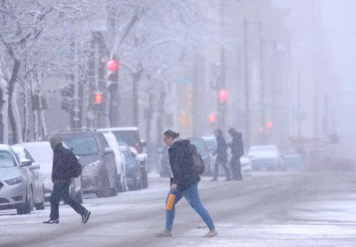 People cross North Broadway Street near East State Street through the snow in Milwaukee on Wednesday, Jan. 25, 2023. The coming days will bring multiple rounds of light snow before the bitter cold arrives at the beginning of next week.