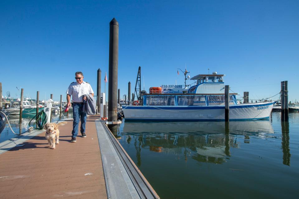 Captain Dan Schade, owner of Classic Boat Rides, a nearly 20-year-old Atlantic Highlands-based provider of public and private charter boat rides on several different boats, walks his dog, Jenny, after checking on his boat, Mariner, in Atlantic Highlands, NJ Thursday, October 6, 2022. 