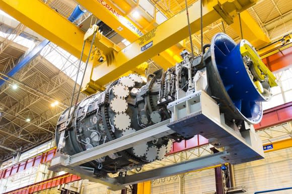 A gas turbine being moved in an indoor manufacturing facility.