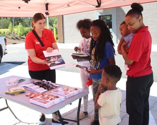 Marisa Stout with Atlanta RMHC, gives books to the Bradford/Watson family including Royalti, from left, Harmony, King Trayvivs, Majesty and Rogeria Shelton.