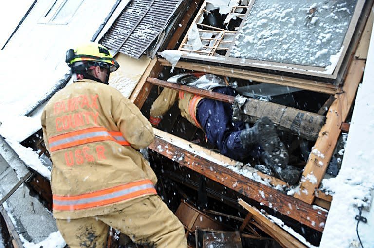 A member of the US Fairfax County search and rescue team from Virginia helps a colleague slide into a crawl space in a destroyed house to look for survivors in Kamaishi