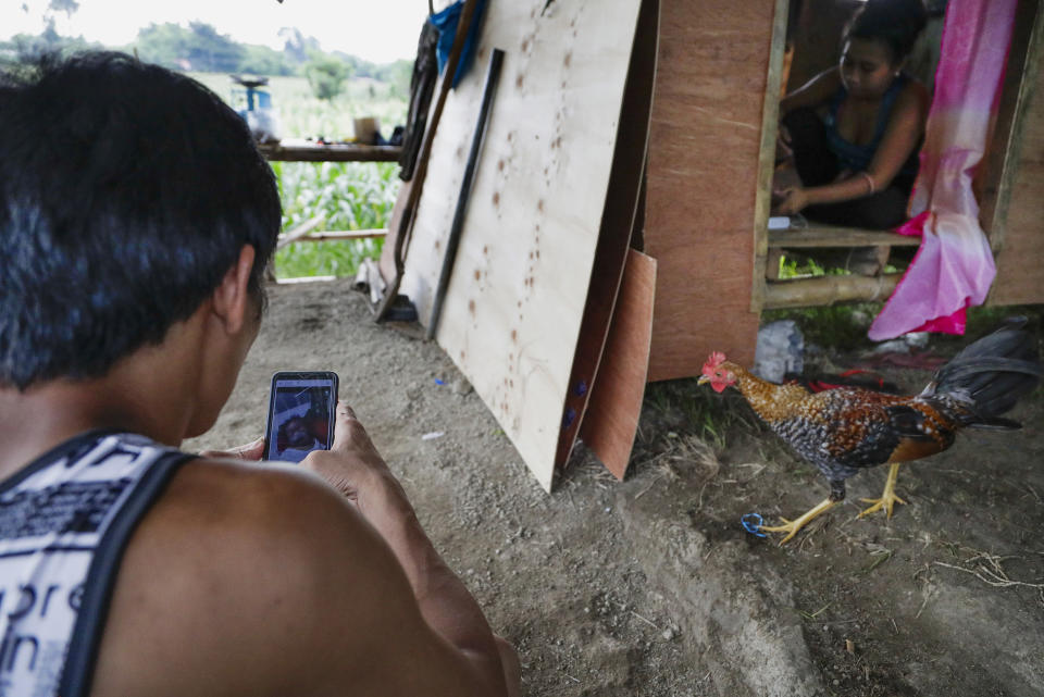 Ronnel Manjares, left, looks at a picture of his son Kobe saved in his smartphone outside their house of their relative in Tanauan, Batangas province, Philippines, Wednesday, July 15, 2020. His 16-day-old son Kobe was heralded as the country's youngest COVID-19 survivor. But the relief and joy proved didn't last. Three days later, Kobe died on June 4 from complications of Hirschsprung disease, a rare birth defect. (AP Photo/Aaron Favila)