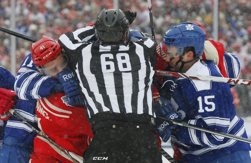 Linesman Scott Driscoll (68) separates Detroit Red Wings right wing Luke Glendening, left, and Toronto Maple Leafs defenseman Paul Ranger (15) during a scuffle in the second period of the Winter Classic outdoor NHL hockey game at Michigan Stadium in Ann Arbor, Mich., Wednesday, Jan. 1, 2014. (AP Photo/Paul Sancya)