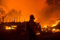 A firefighter watches the Lake Hughes fire consumes a home in Angeles National Forest on Wednesday, Aug. 12, 2020, north of Santa Clarita, Calif. (AP Photo/Ringo H.W. Chiu)